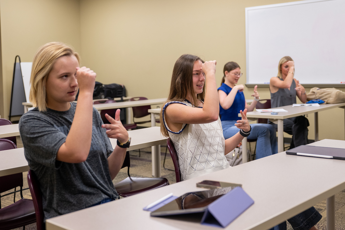 Interpreter training students practicing sign language in the classroom. 