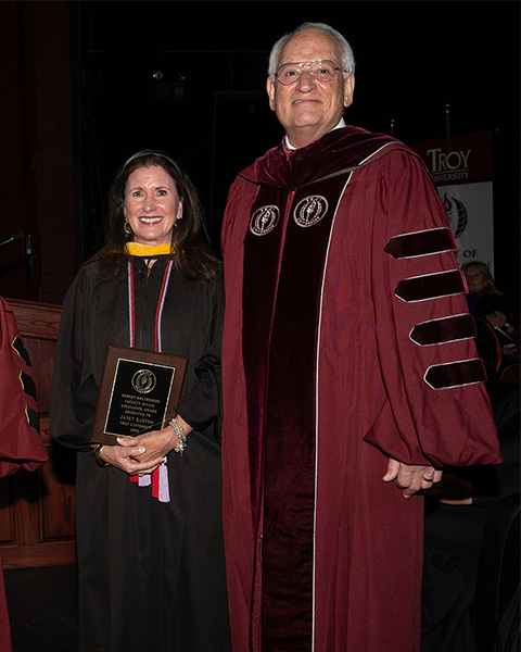 Chancellor Jack Hawkins stands with a graduate at Troy University's commencement ceremony