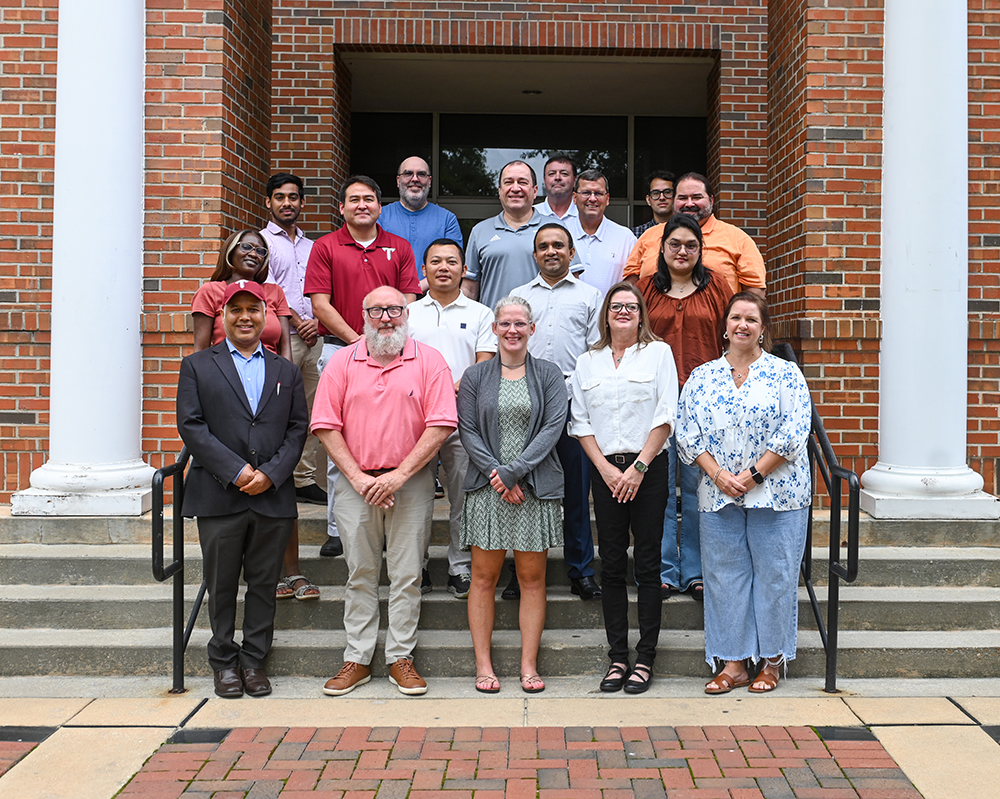 Professor with Students working around a table with books and worksheets.