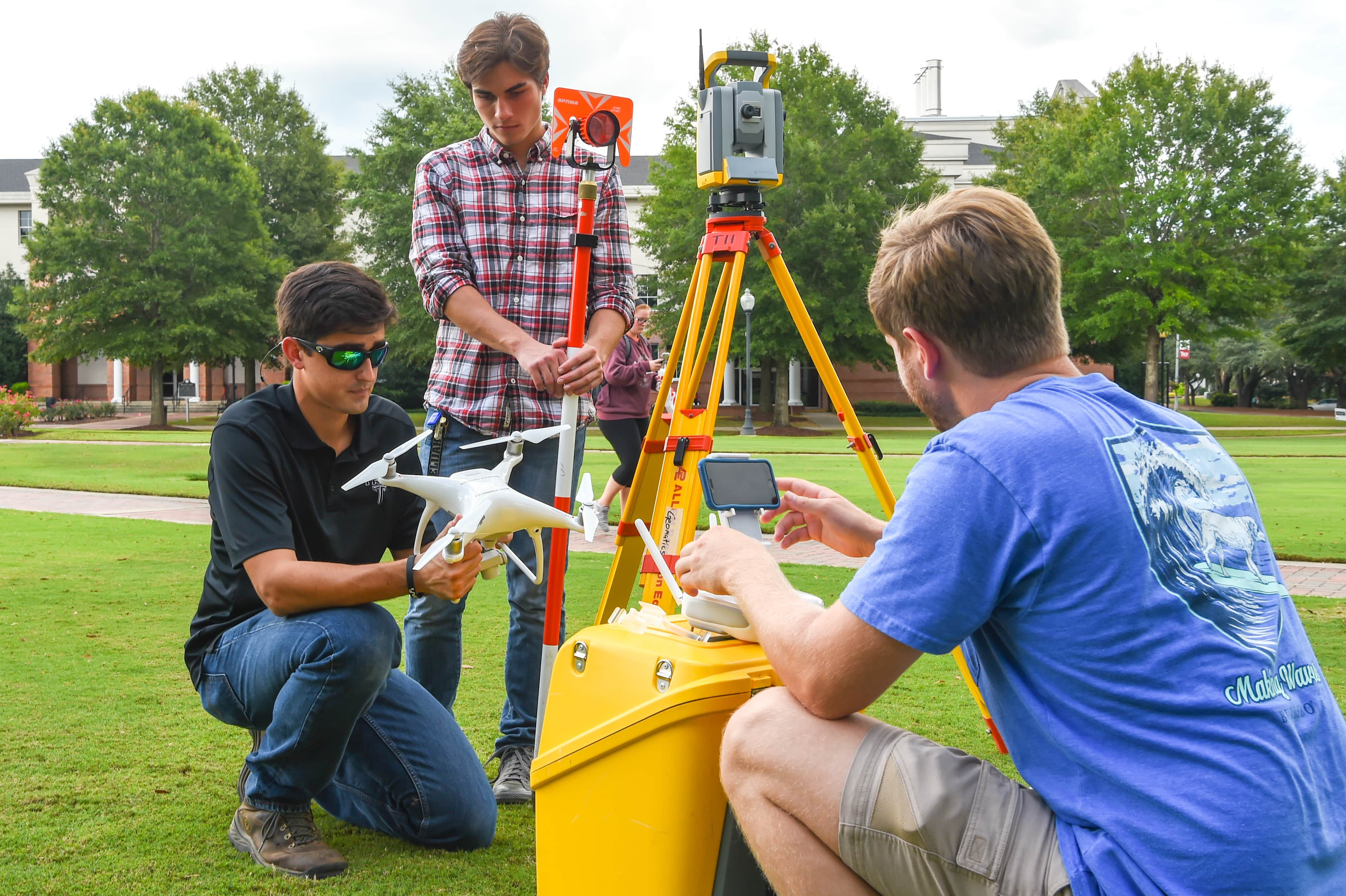 Geomatics students using surveying equipment on Troy University quad. 