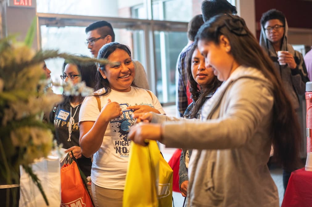 Female students examine items in Geo Day backpack presented to each high school student