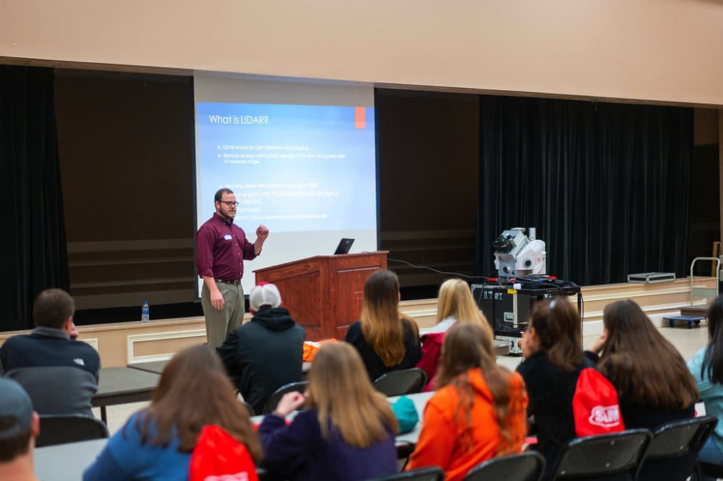 Professional answers the question “What is LIDAR?” in a Geo Day session with a 3-D laser scanner on display