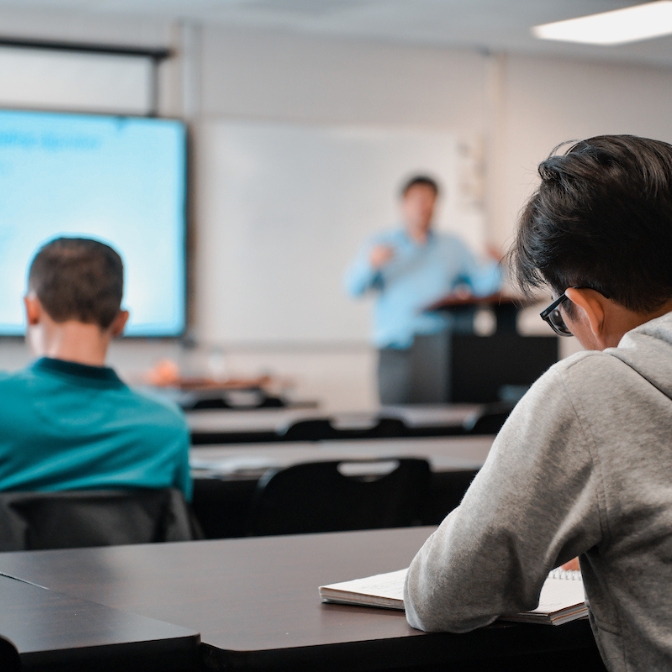 TROY student taking notes in class