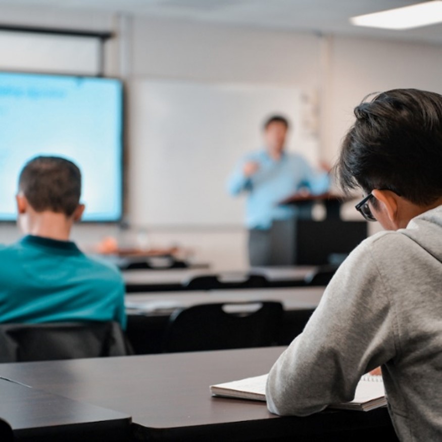 TROY student taking notes in class