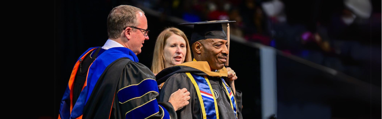 Three people at a graduation ceremony