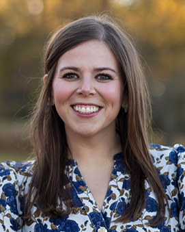woman in floral dress named Caroline smiling at the camera.