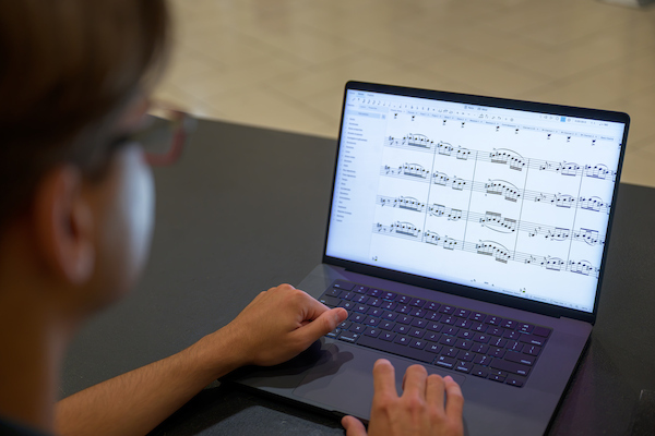 Student working on a computer to create a music sheet for class