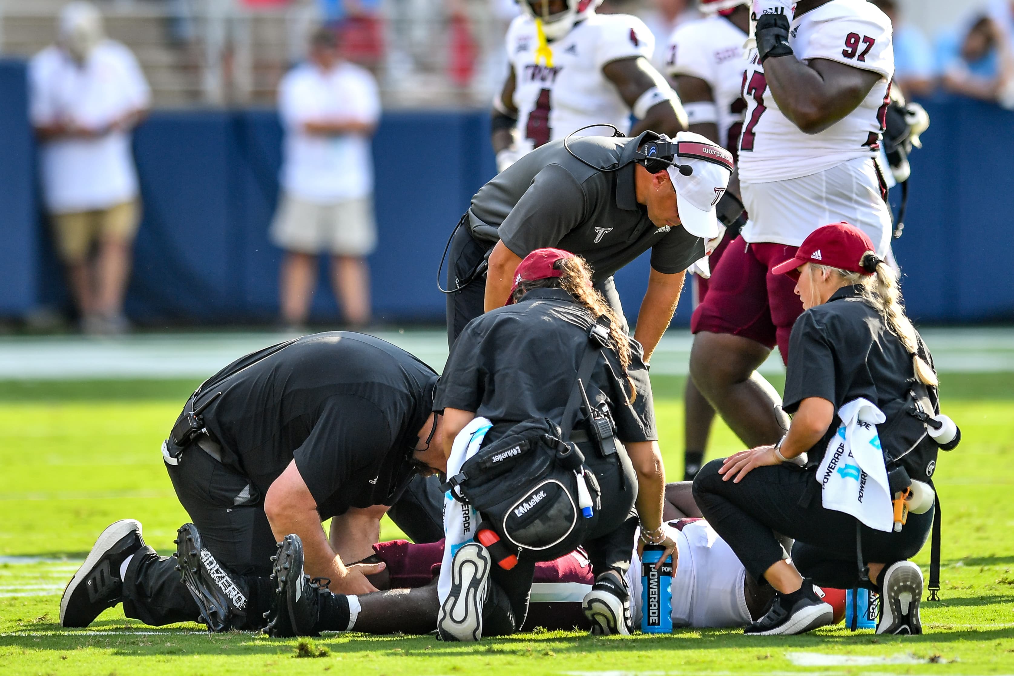 Students and Athletic Trainer assessing a football player's injury.