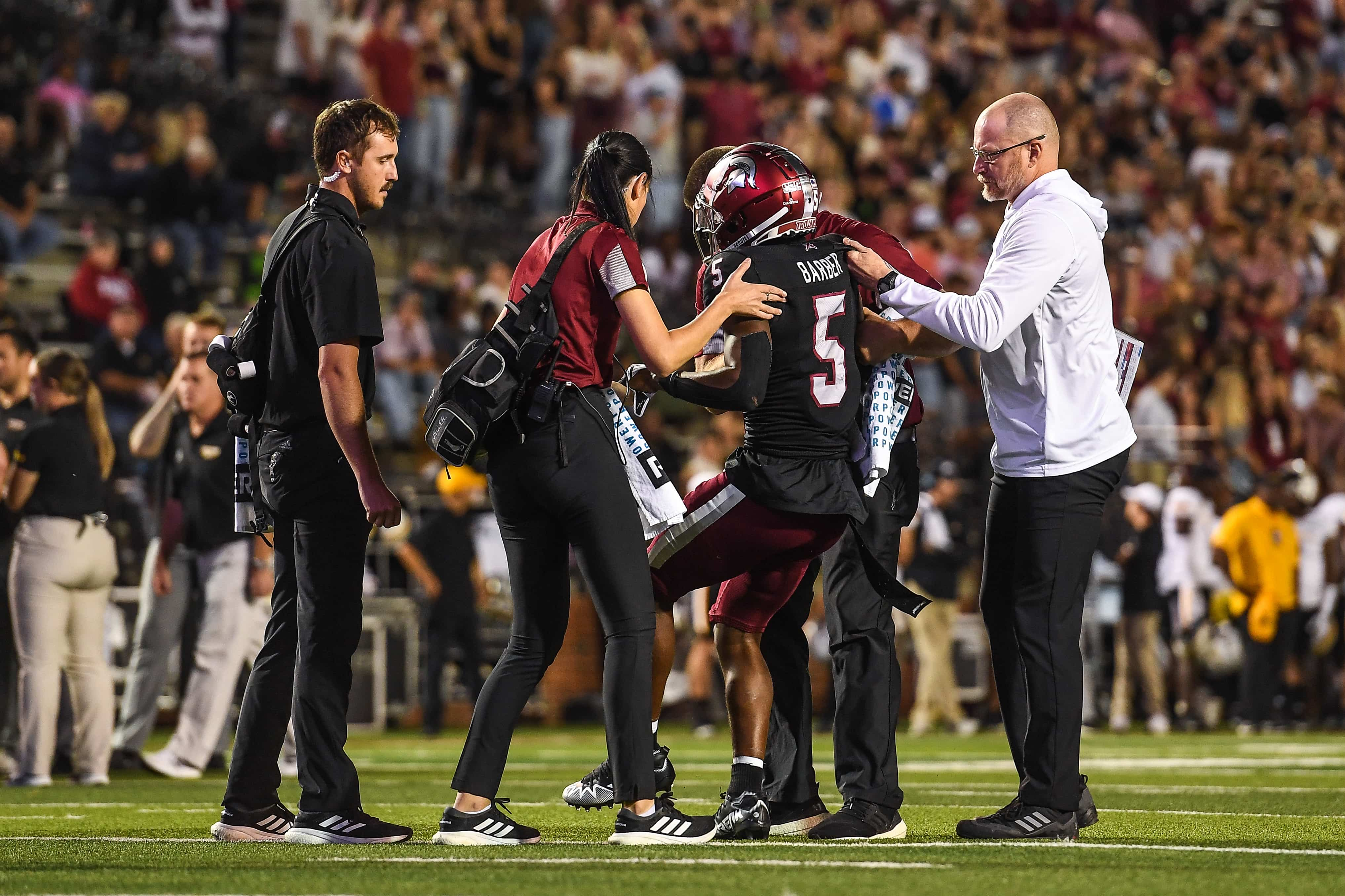 Athletic Trainers helping an injured player off the field.