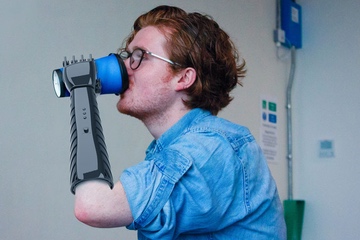 3D Printed Prosethic Hand being used by young man to drink from a cup.