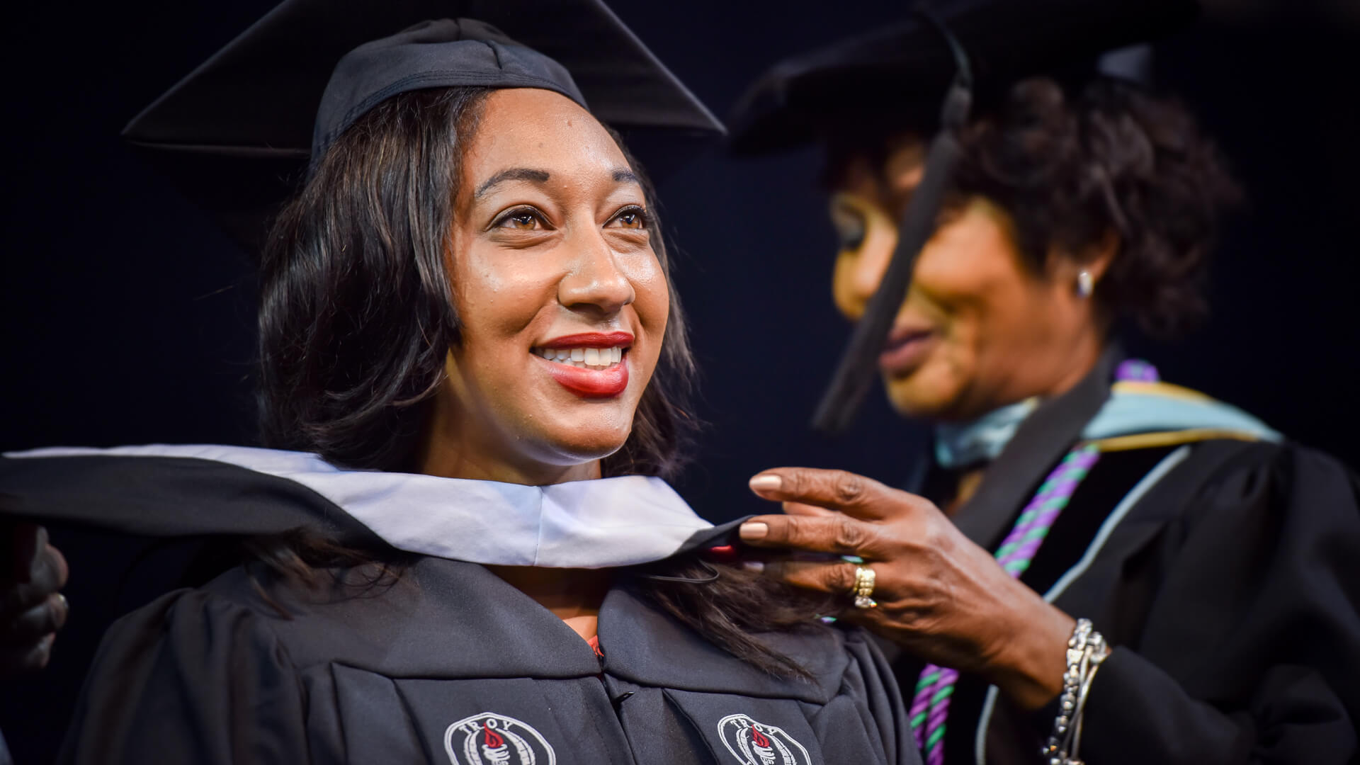 Close-up of graduates looking at the stage with their hands over their hearts