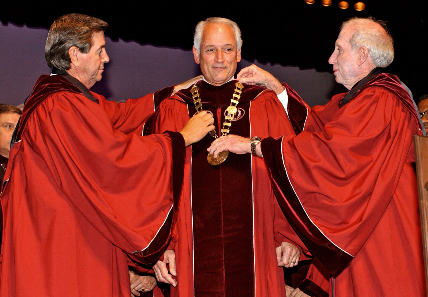 Alabama Gov. Bob Riley, left, and Board of Trustees President Pro-tem Dr. Doug Hawkins place a new medallion around Chancellor Dr. Jack Hawkins, Jr.’s neck, signifying the official transition to Troy University from Troy State University.