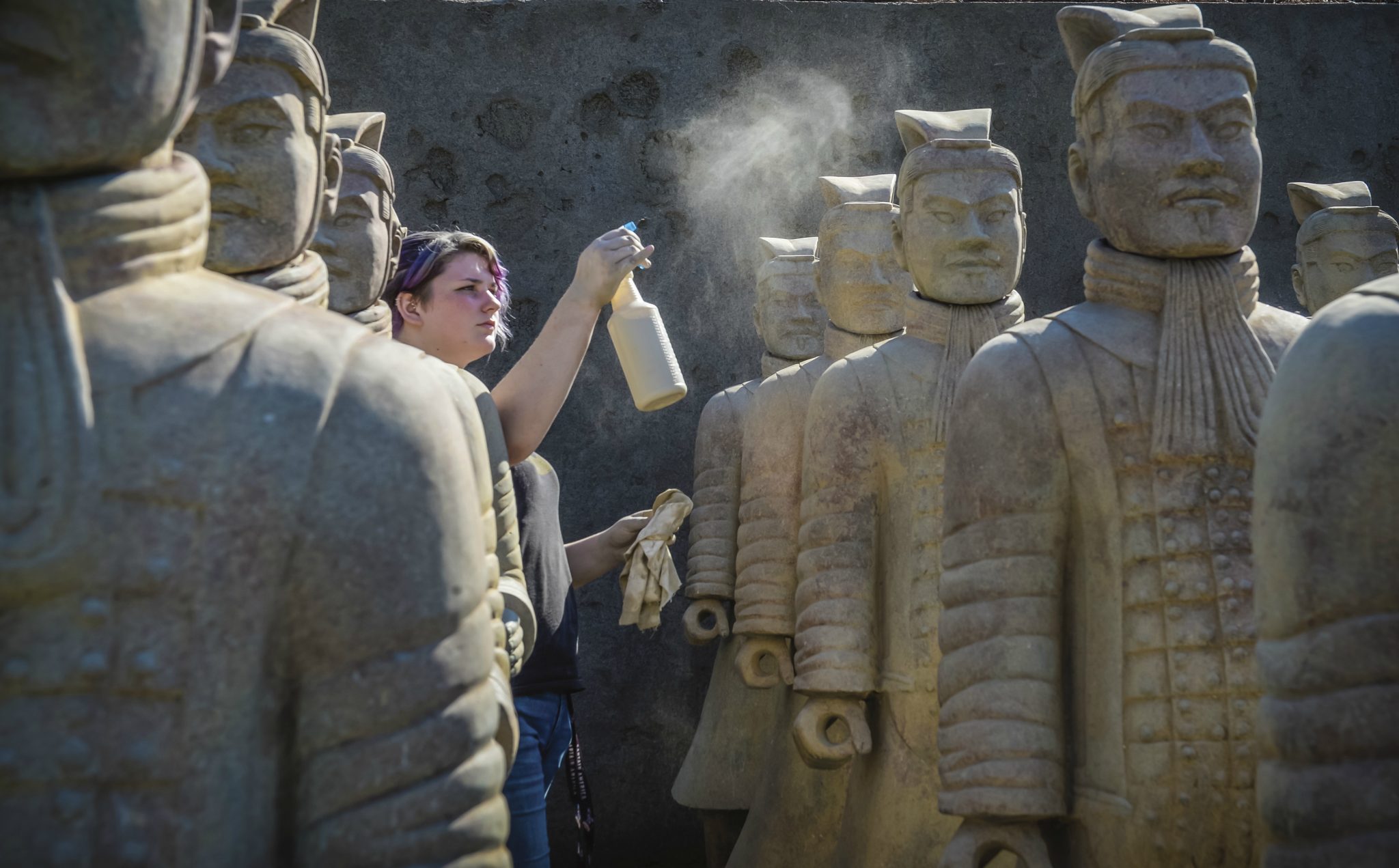 TROY student preparing terra cotta warriors for installation.