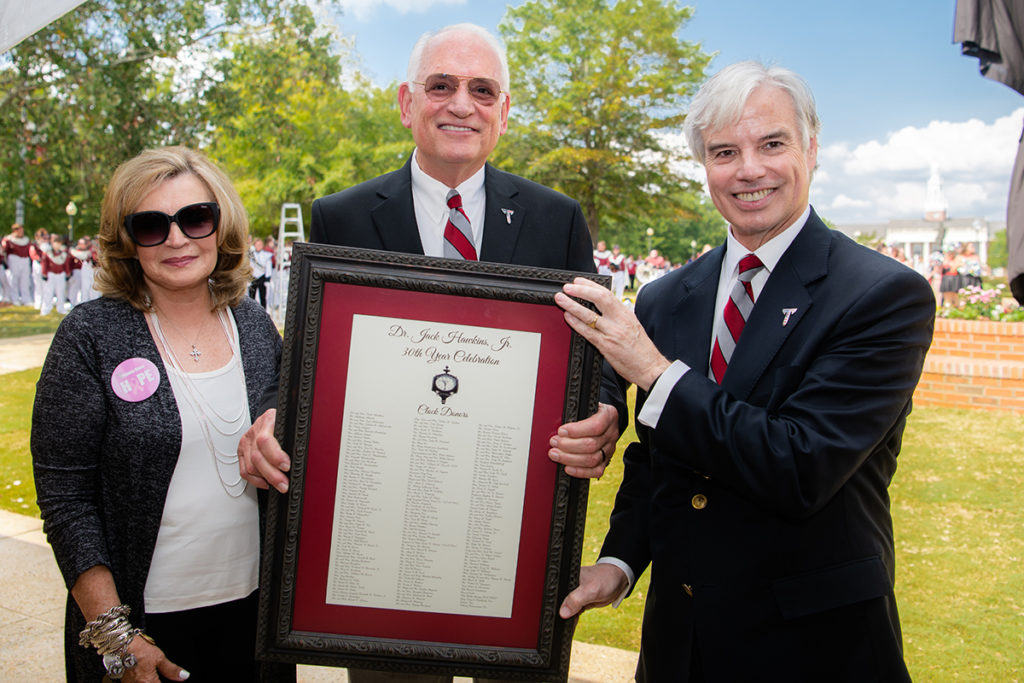 Maj. Gen. Walter Givhan, USAF ret., Senior Vice Chancellor for Advancement and Economic Development, presents Dr. and Mrs. Jack Hawkins, Jr. with a list of donors who helped fund the clock, unveiled Saturday in honor of Dr. Hawkins’ 30th year as the University’s Chancellor.