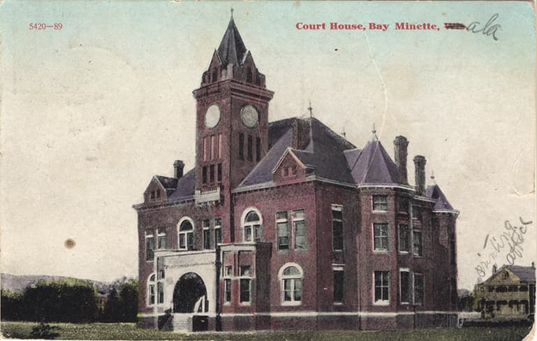 Color print of the two-story Baldwin County Courthouse and another building in Bay Minette, Alabama. Postmarked June 22, 1910.