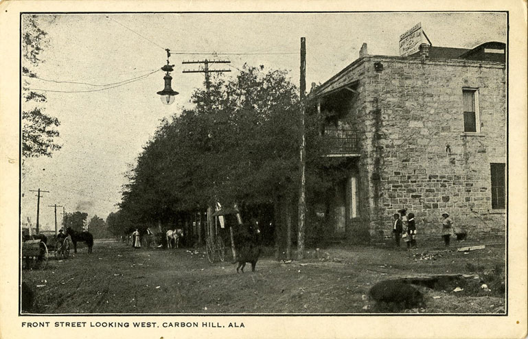 Black and white photograph of unpaved Front Street in Carbon Hill, Alabama showing a two-story commercial building.