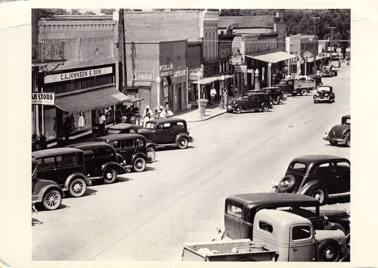 Black and white photo of commercial buildings on Main Street in Greensboro, Alabama.