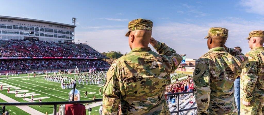 Military members saluting at the Veterans Memorial Stadium.