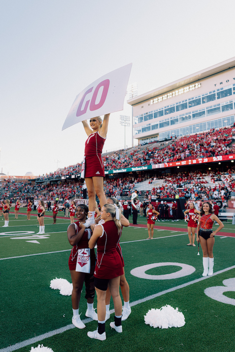 Cheerleaders on the football field holding a GO sign
