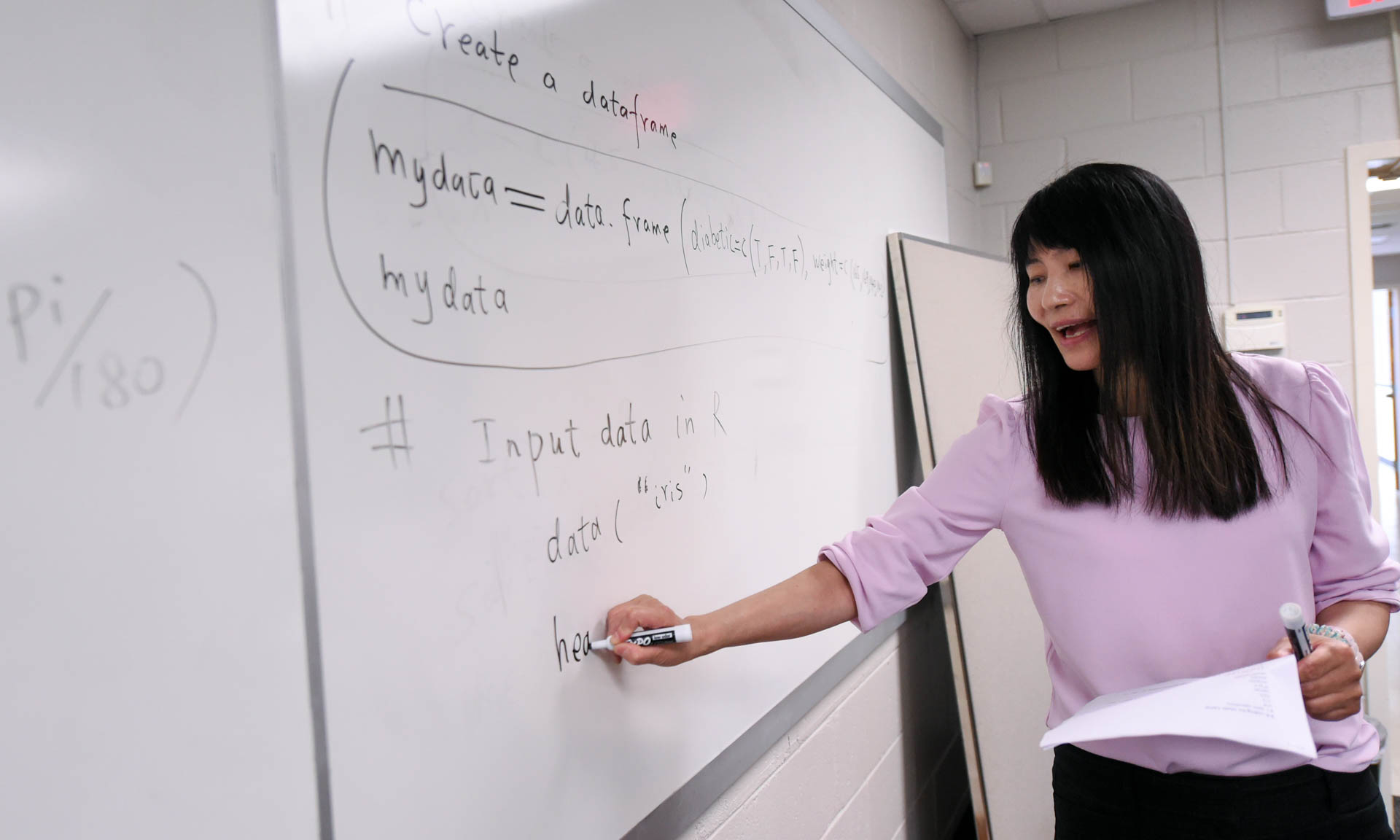 Professor works out math problem on whiteboard