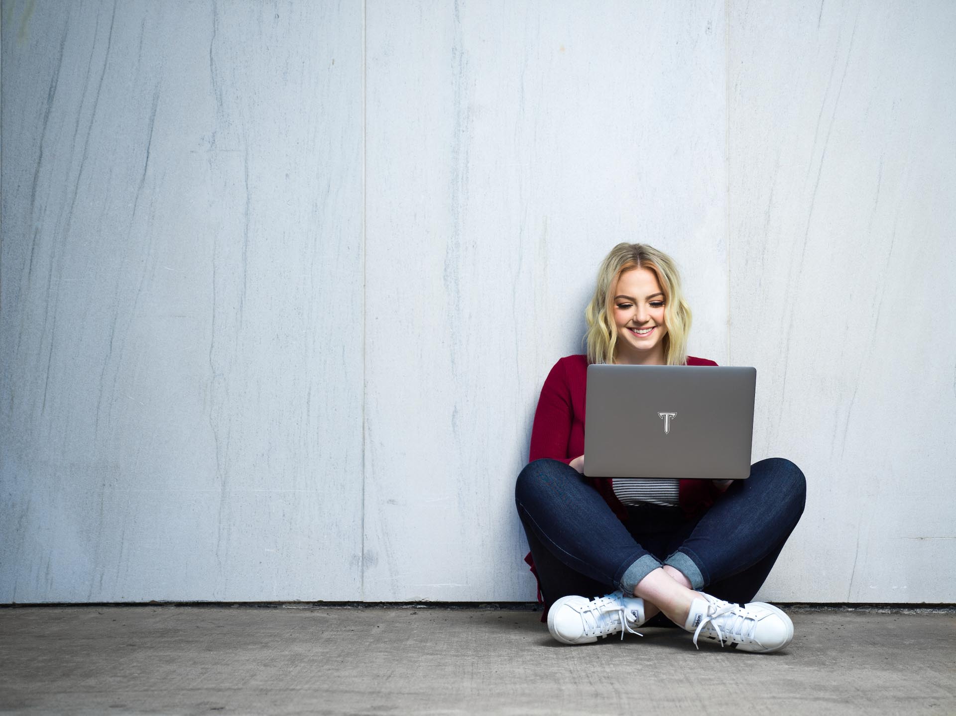 student looking at camera smiling while holding computer 