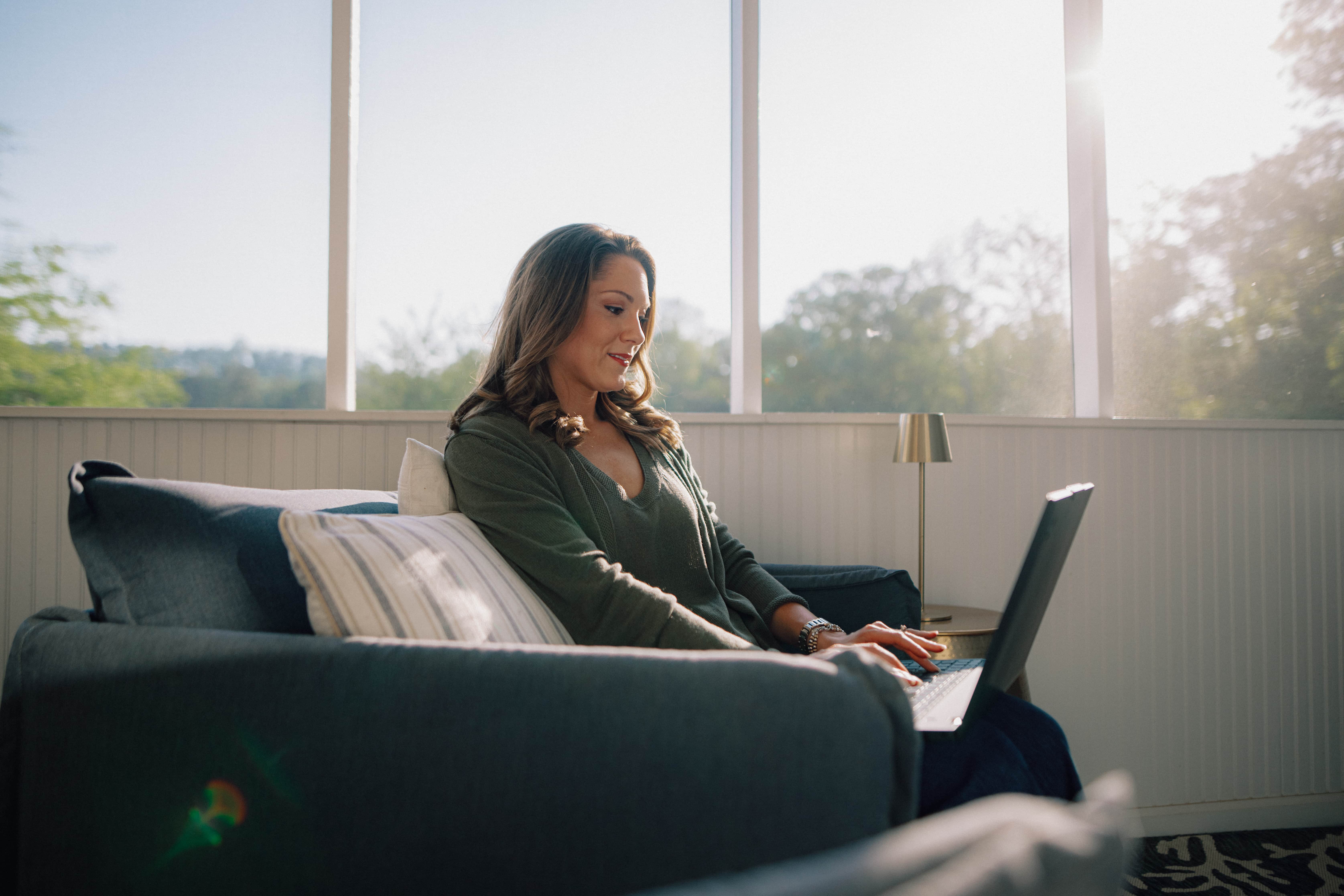 Woman sitting on a couch using a laptop.
