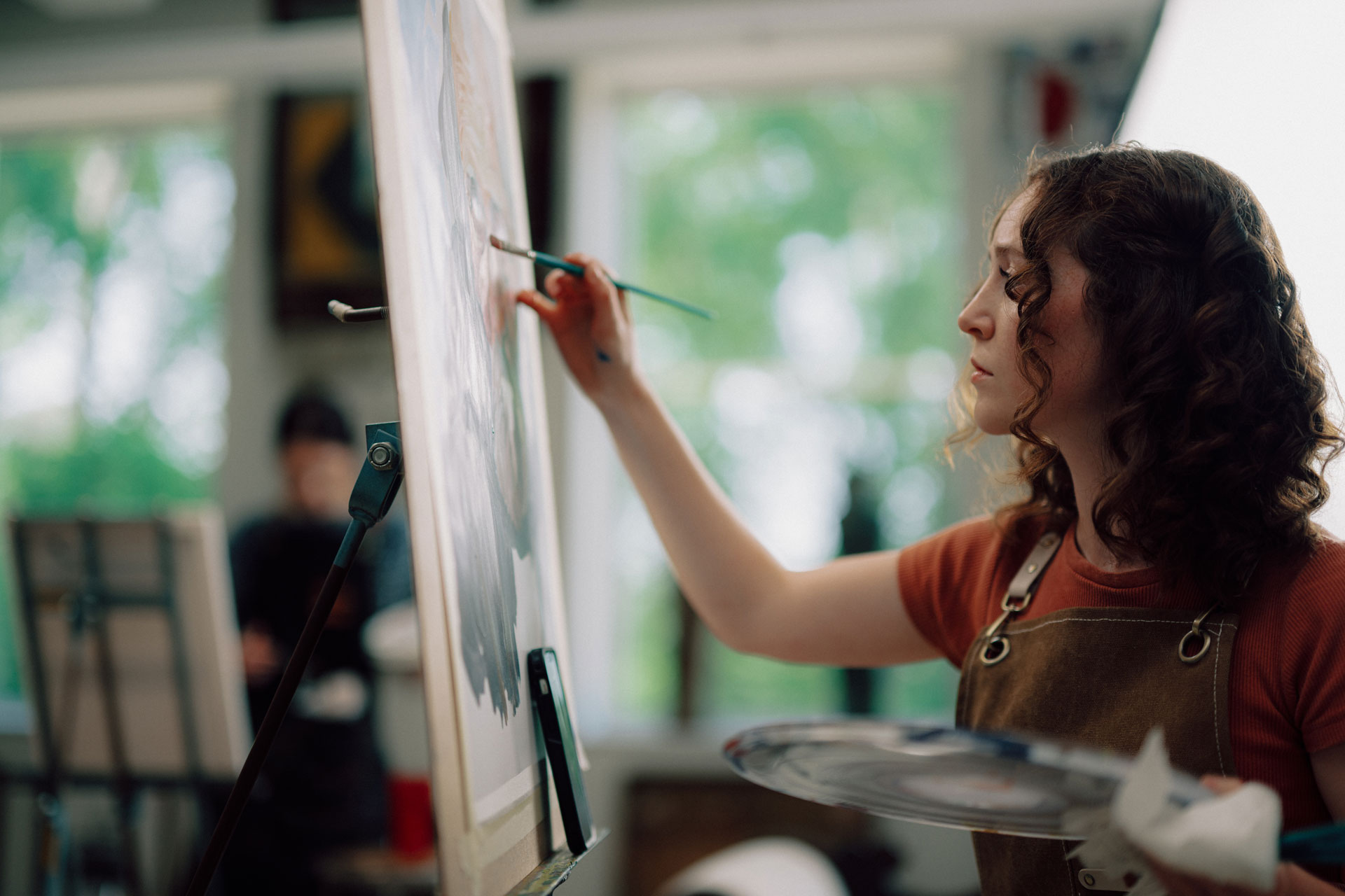 A TROY art and design student paints with her classmates in the International Arts Center.