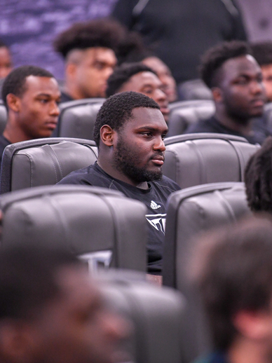 Football player sitting in a meeting.