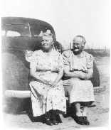 [Sept. 29, 1948]  Sisters Mary McNeil (left) and [Emilia] McNeil Smith sitting on car bumper.