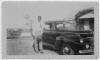 Ms. Annie Jane Martin's son, Isaac Porter Martin, in grandmother's yard 115 Hall St., Abbeville, AL. With 1940s automobile, coupe, possibly Pontiac. Ca. 1940.