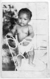 Professional photo of Willadean Martin as a ca. 6-month old. Standing on chair, wearing only diaper.